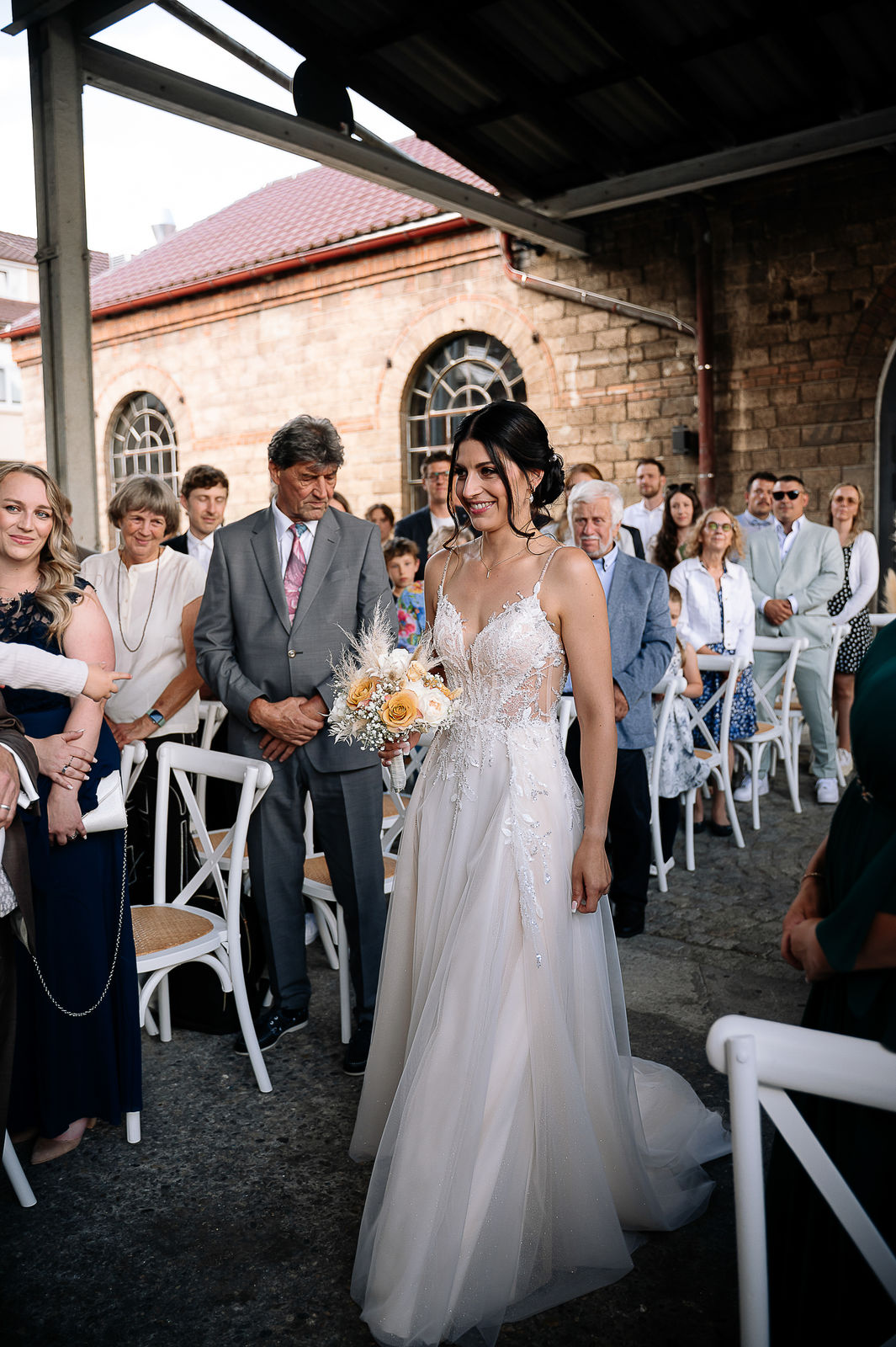 Brautpaar Sara und Olli bei ihrer Hochzeit in der Motorworld Village Metzingen vor historischer Backsteinkulisse.