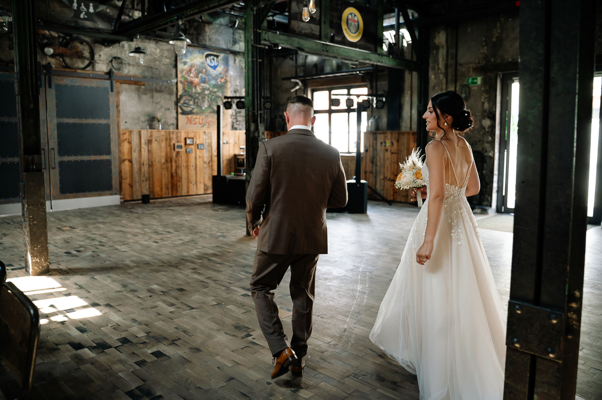 Brautpaar Sara und Olli bei ihrer Hochzeit in der Motorworld Village Metzingen vor historischer Backsteinkulisse.
