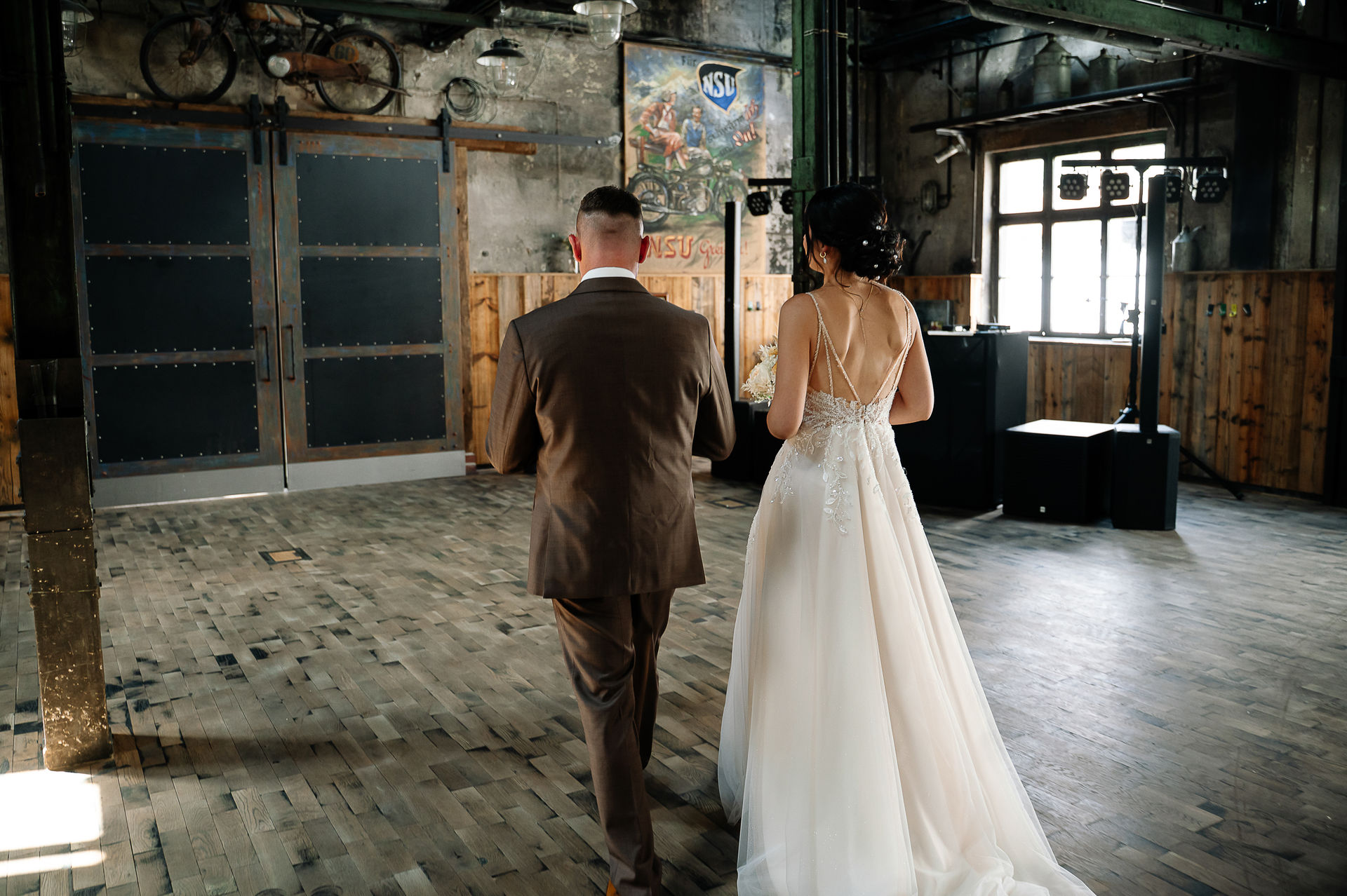 Brautpaar Sara und Olli bei ihrer Hochzeit in der Motorworld Village Metzingen vor historischer Backsteinkulisse.