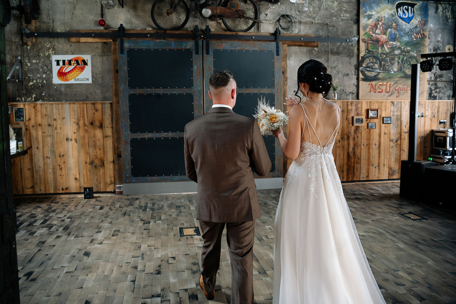 Brautpaar Sara und Olli bei ihrer Hochzeit in der Motorworld Village Metzingen vor historischer Backsteinkulisse.