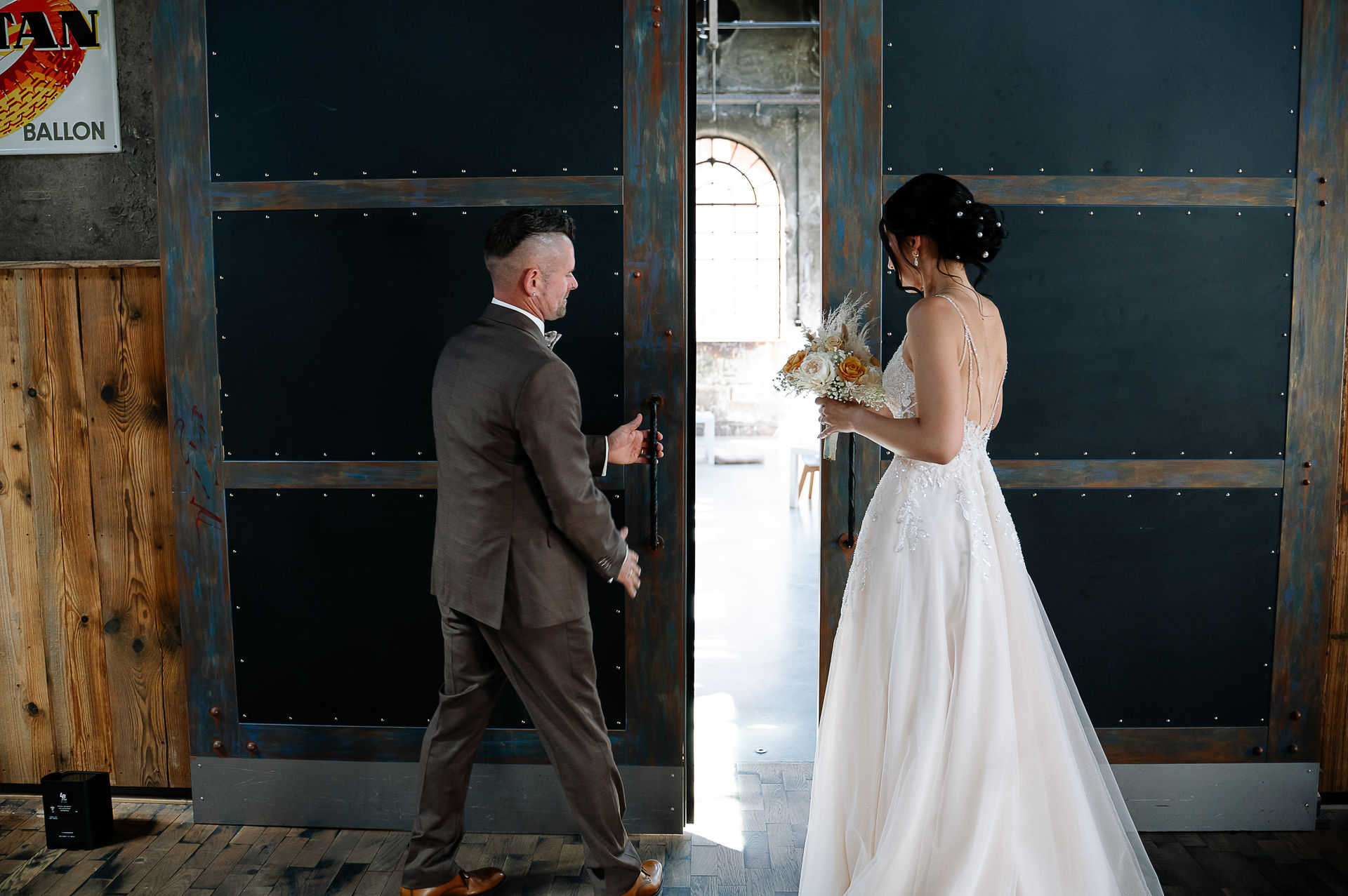 Brautpaar Sara und Olli bei ihrer Hochzeit in der Motorworld Village Metzingen vor historischer Backsteinkulisse.