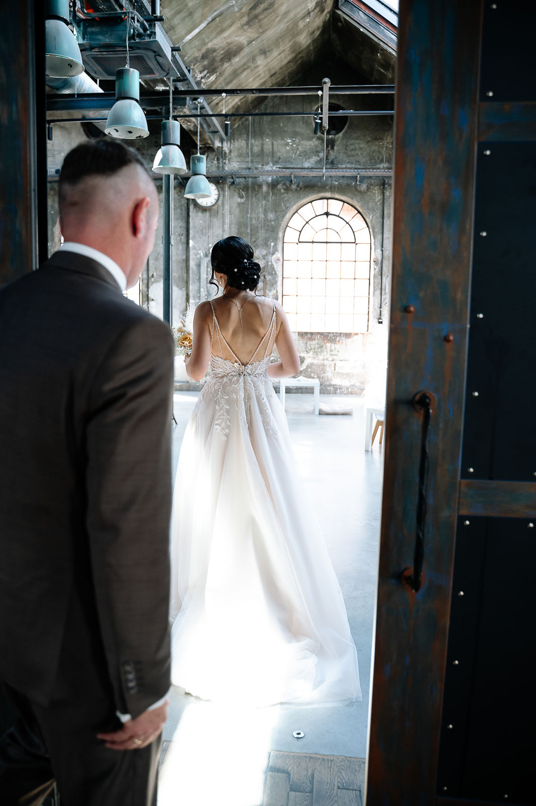 Brautpaar Sara und Olli bei ihrer Hochzeit in der Motorworld Village Metzingen vor historischer Backsteinkulisse.