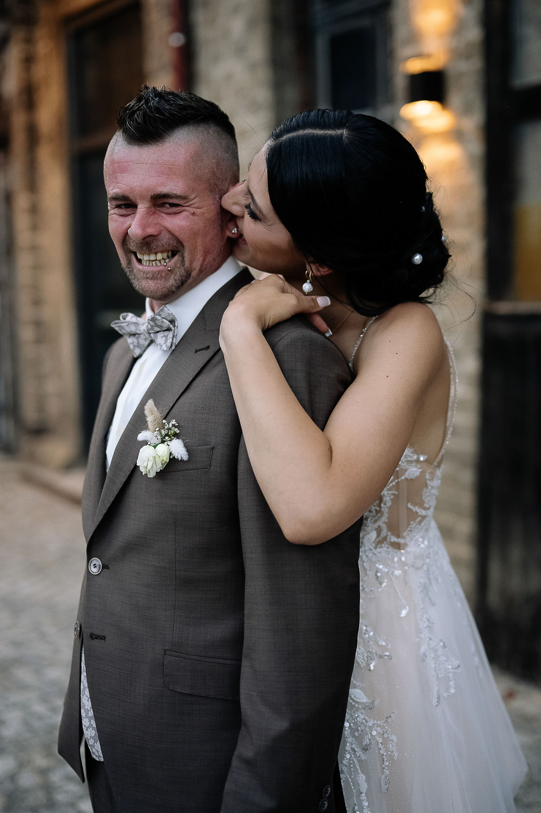 Brautpaar Sara und Olli bei ihrer Hochzeit in der Motorworld Village Metzingen vor historischer Backsteinkulisse.