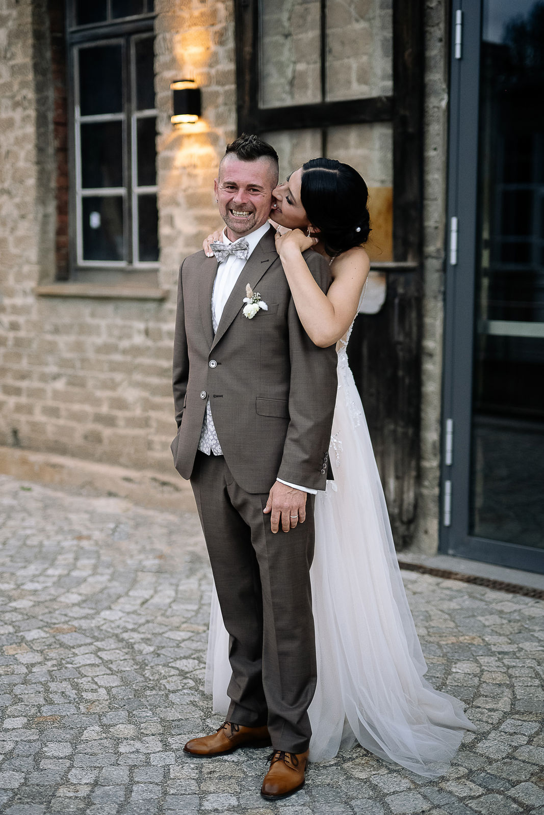 Brautpaar Sara und Olli bei ihrer Hochzeit in der Motorworld Village Metzingen vor historischer Backsteinkulisse.