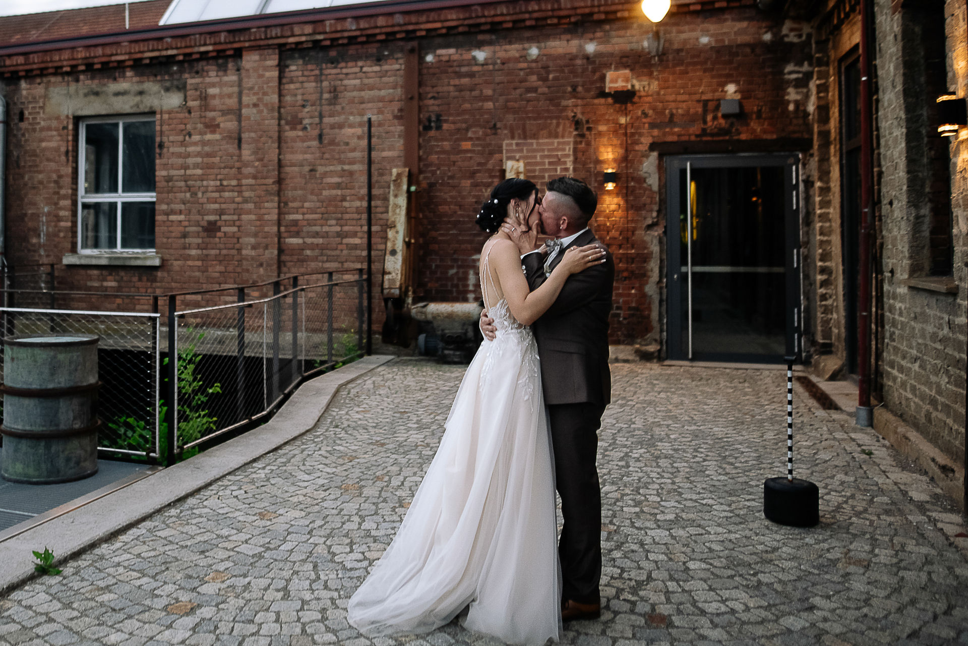 Brautpaar Sara und Olli bei ihrer Hochzeit in der Motorworld Village Metzingen vor historischer Backsteinkulisse.