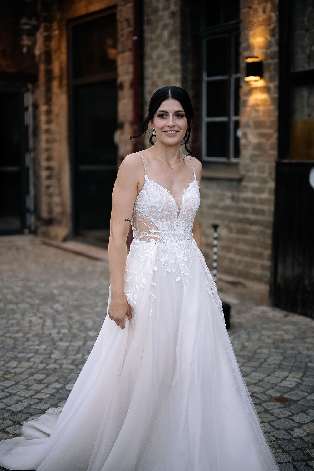 Brautpaar Sara und Olli bei ihrer Hochzeit in der Motorworld Village Metzingen vor historischer Backsteinkulisse.