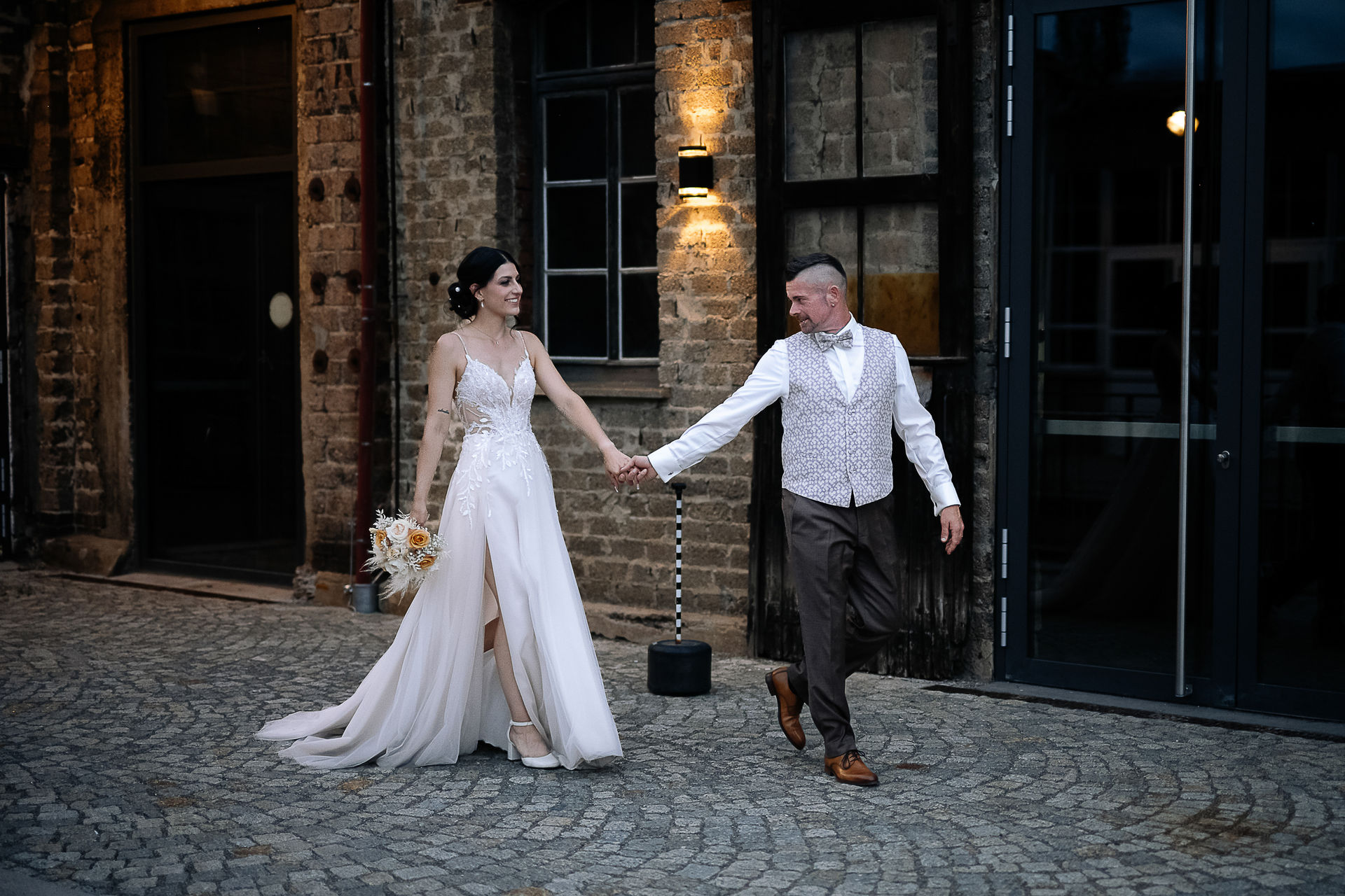 Brautpaar Sara und Olli bei ihrer Hochzeit in der Motorworld Village Metzingen vor historischer Backsteinkulisse.