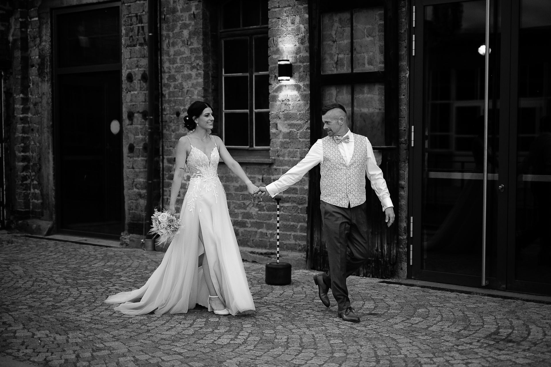 Brautpaar Sara und Olli bei ihrer Hochzeit in der Motorworld Village Metzingen vor historischer Backsteinkulisse.