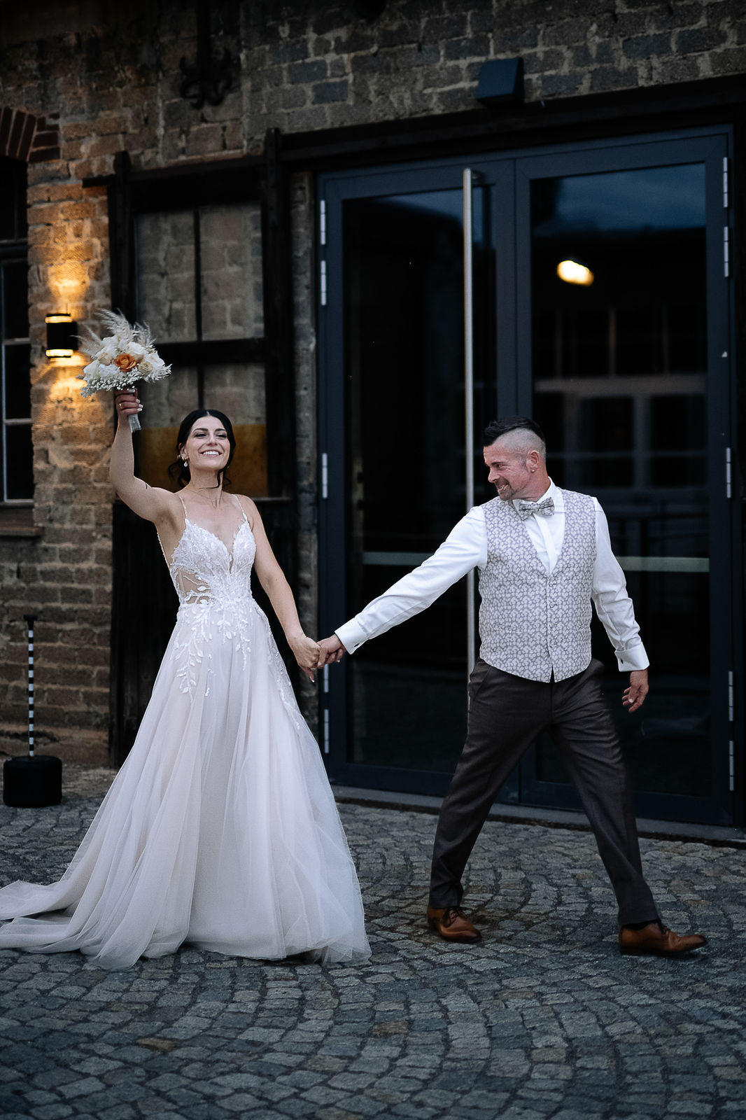 Brautpaar Sara und Olli bei ihrer Hochzeit in der Motorworld Village Metzingen vor historischer Backsteinkulisse.