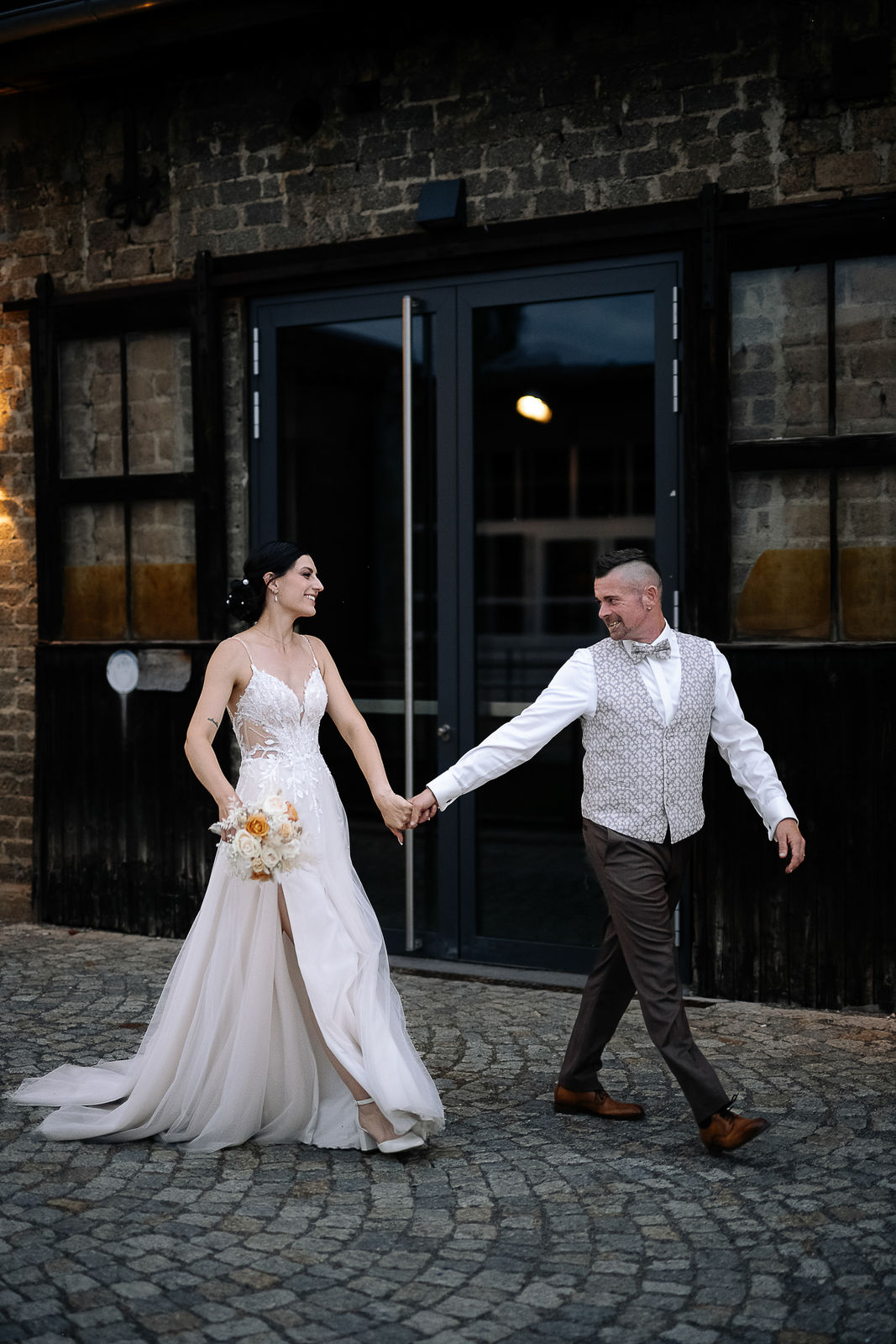 Brautpaar Sara und Olli bei ihrer Hochzeit in der Motorworld Village Metzingen vor historischer Backsteinkulisse.