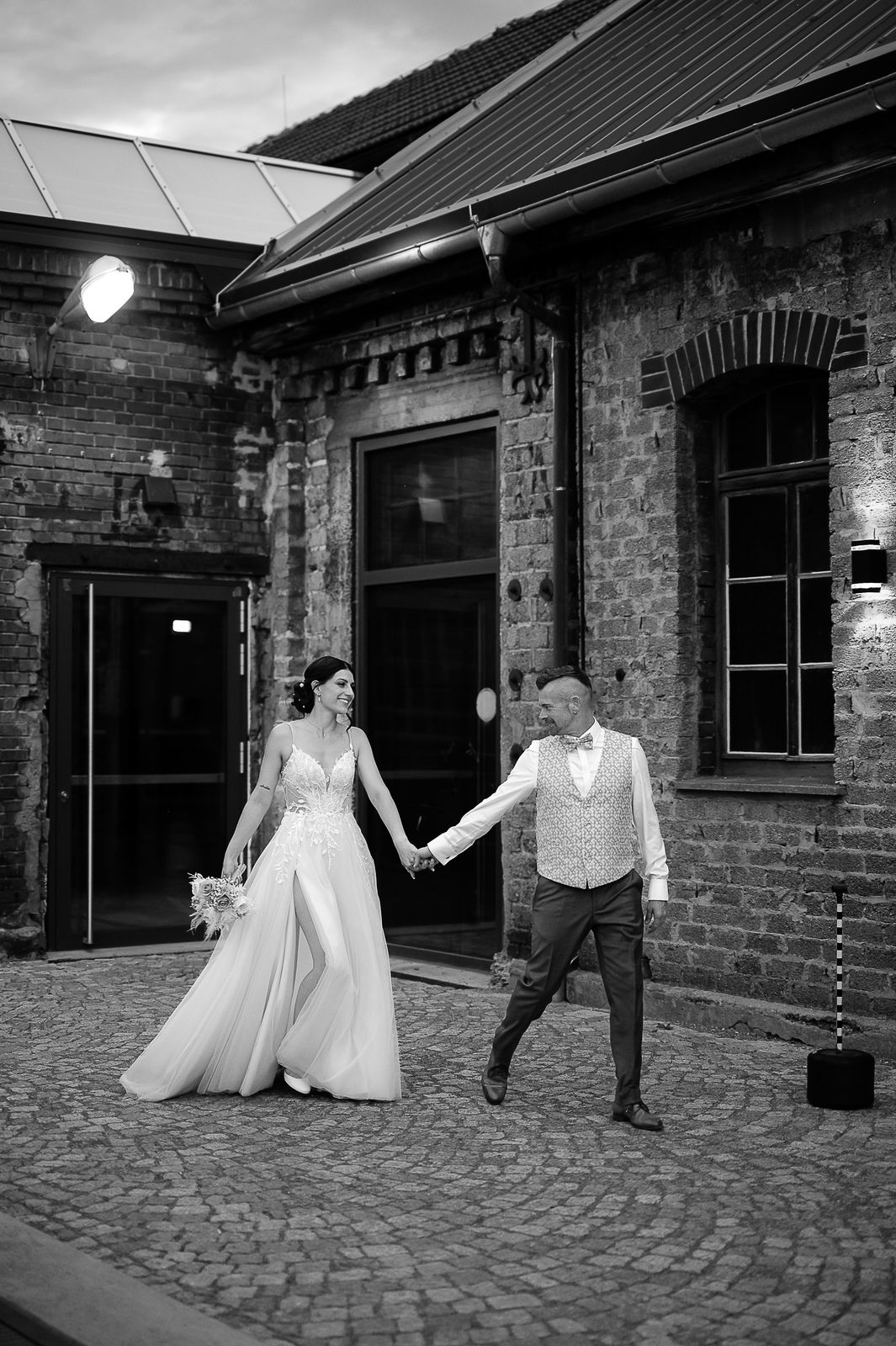Brautpaar Sara und Olli bei ihrer Hochzeit in der Motorworld Village Metzingen vor historischer Backsteinkulisse.