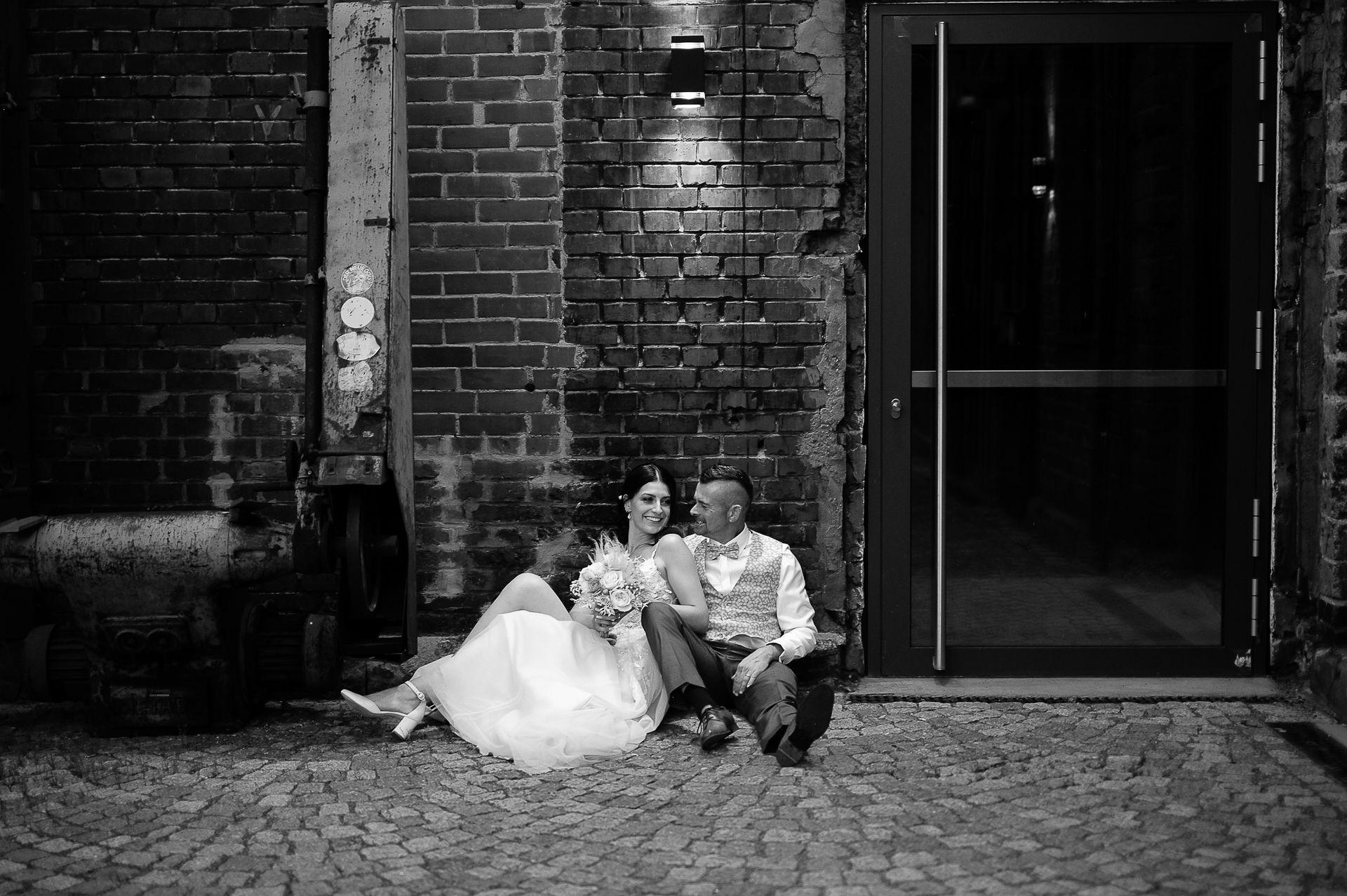 Brautpaar Sara und Olli bei ihrer Hochzeit in der Motorworld Village Metzingen vor historischer Backsteinkulisse.