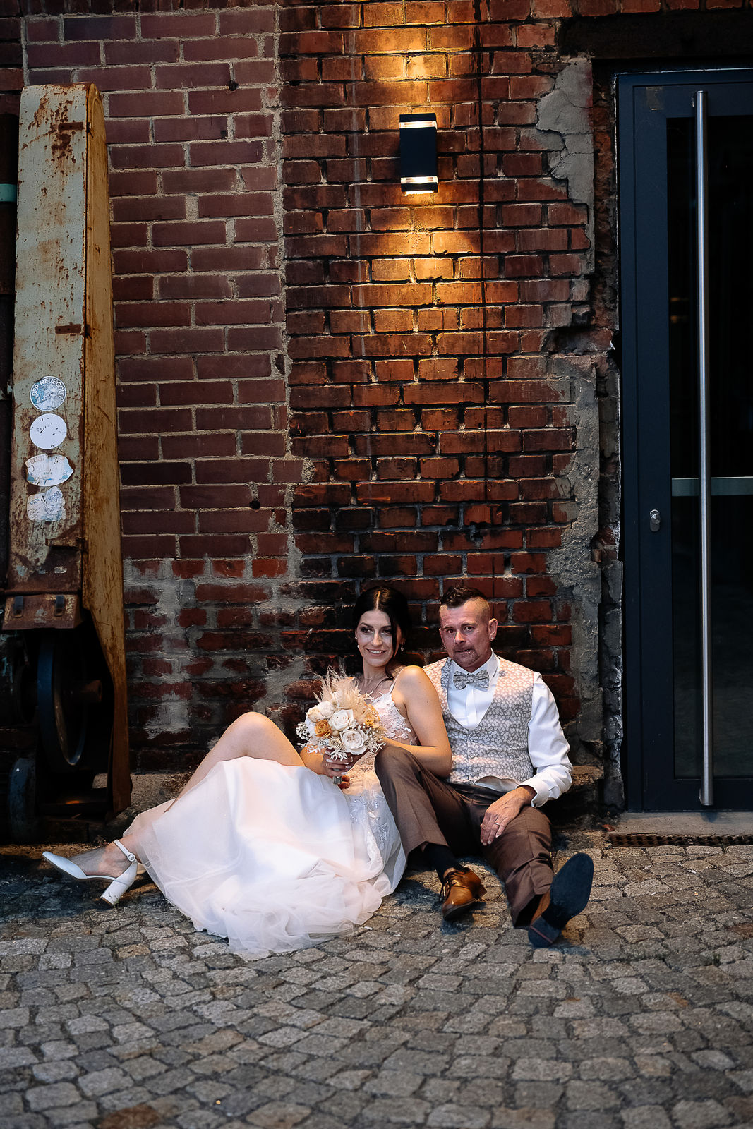 Brautpaar Sara und Olli bei ihrer Hochzeit in der Motorworld Village Metzingen vor historischer Backsteinkulisse.
