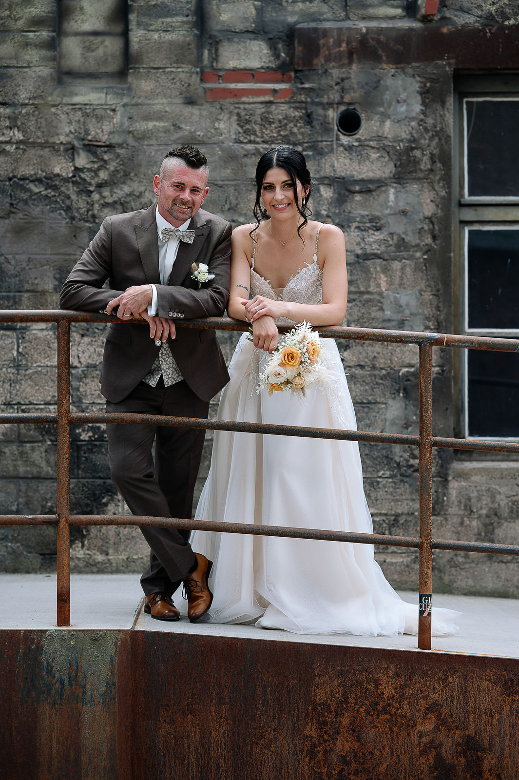 Brautpaar Sara und Olli bei ihrer Hochzeit in der Motorworld Village Metzingen vor historischer Backsteinkulisse.