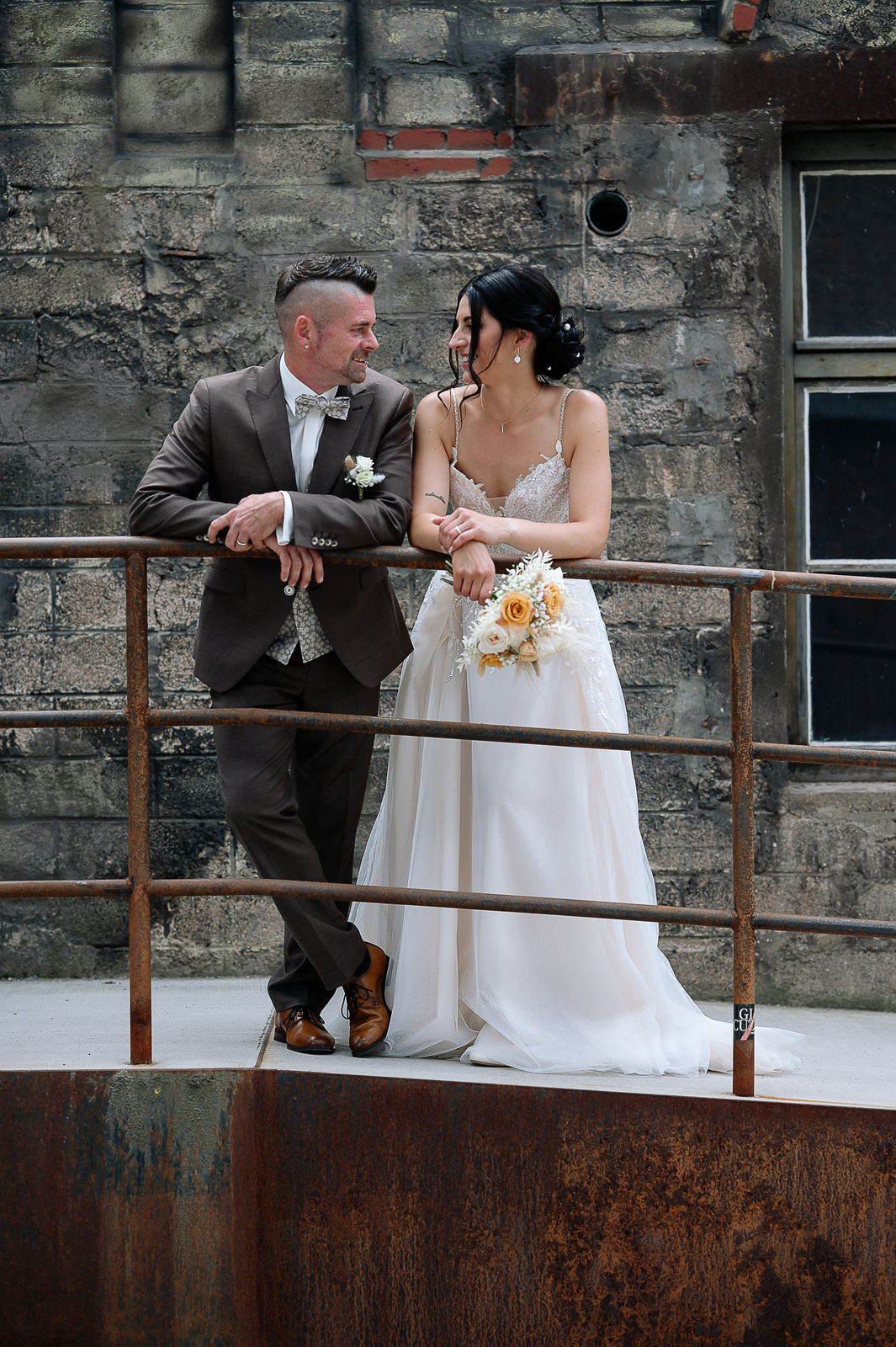 Brautpaar Sara und Olli bei ihrer Hochzeit in der Motorworld Village Metzingen vor historischer Backsteinkulisse.