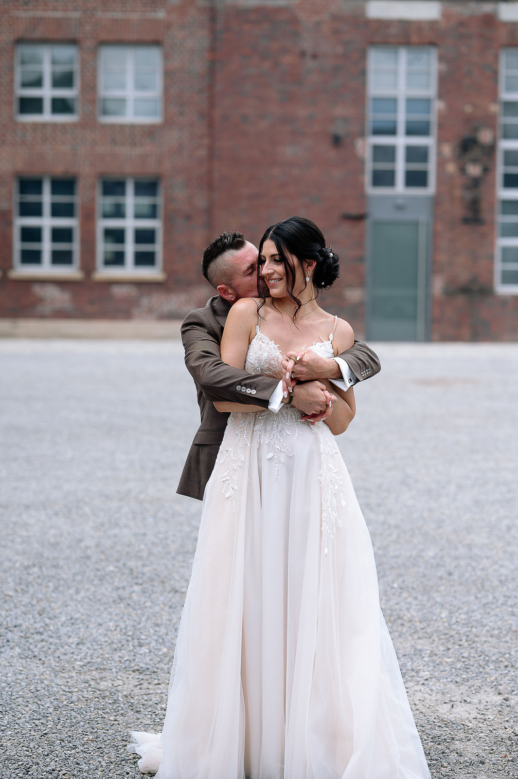 Brautpaar Sara und Olli bei ihrer Hochzeit in der Motorworld Village Metzingen vor historischer Backsteinkulisse.