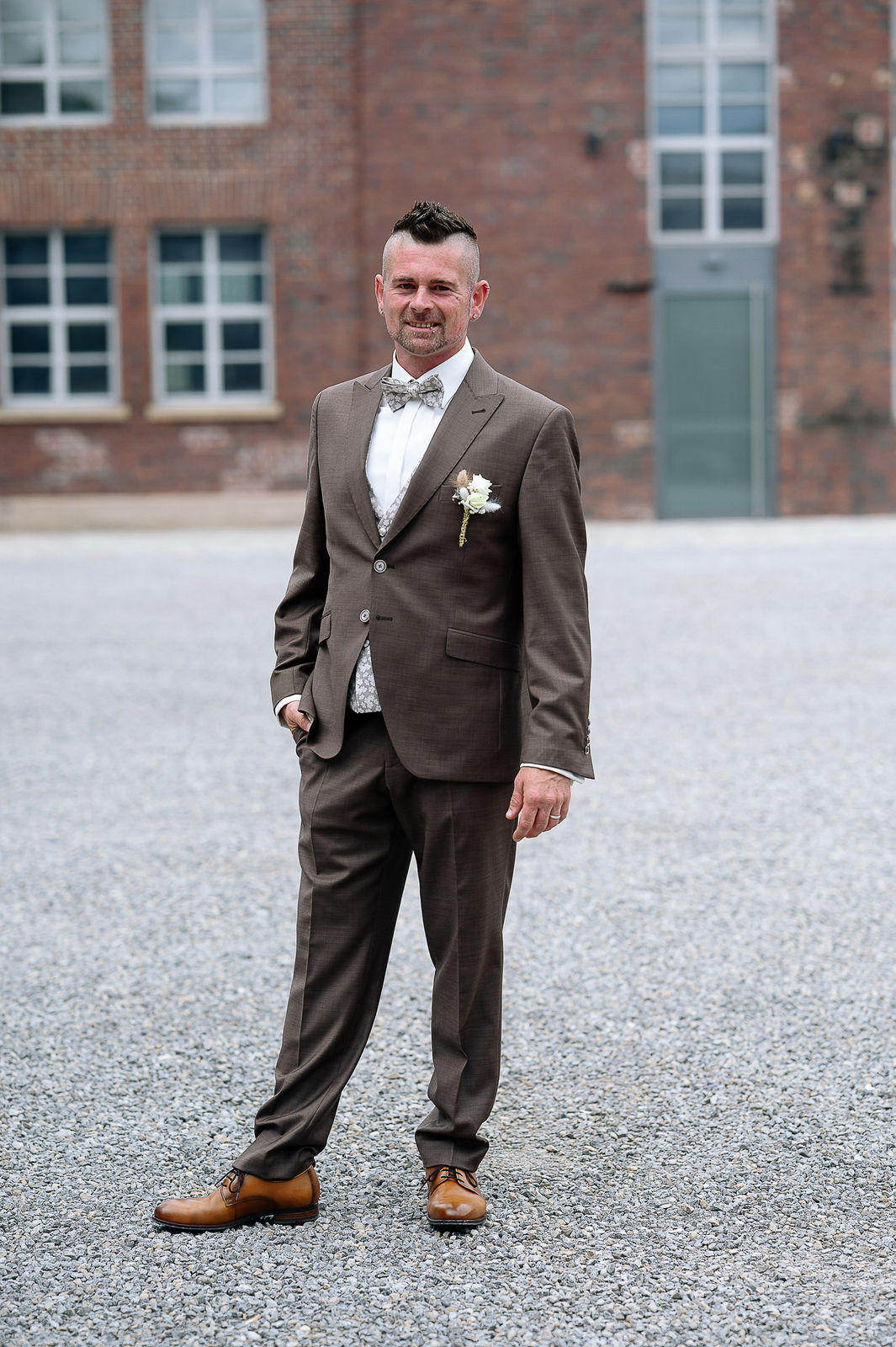 Brautpaar Sara und Olli bei ihrer Hochzeit in der Motorworld Village Metzingen vor historischer Backsteinkulisse.